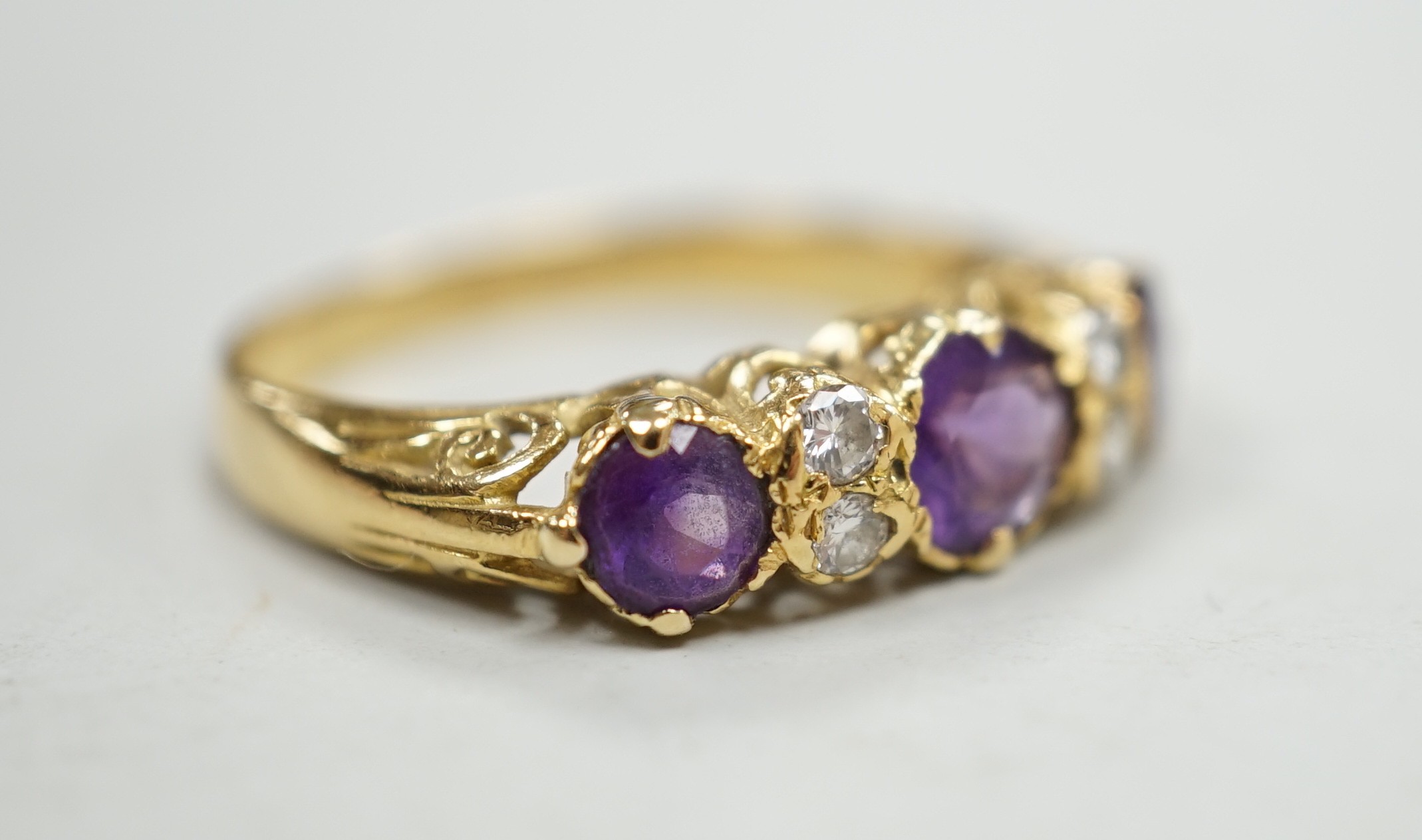 An 18ct, three stone amethyst and four stone diamond set half hoop ring, size Q/R, gross weight 4 grams.